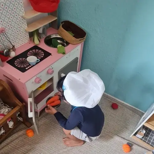 Ein kleines Kind spielt konzentriert in der Spielküche der Kindertagespflege Kunterbunt am Brudergrund in Erbach.