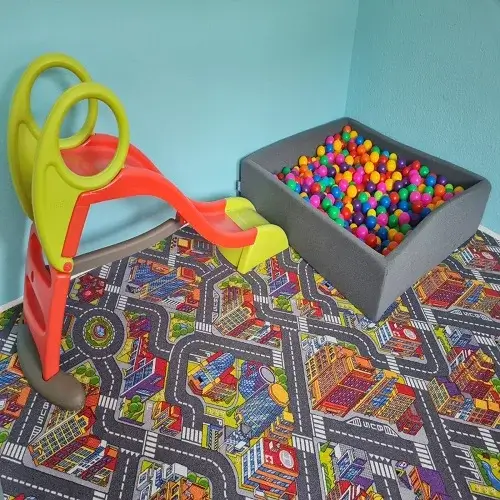 Eine bunte Spielecke mit Rutsche und Bällebad im Innenraum der Kindertagespflege Kunterbunt am Brudergrund.